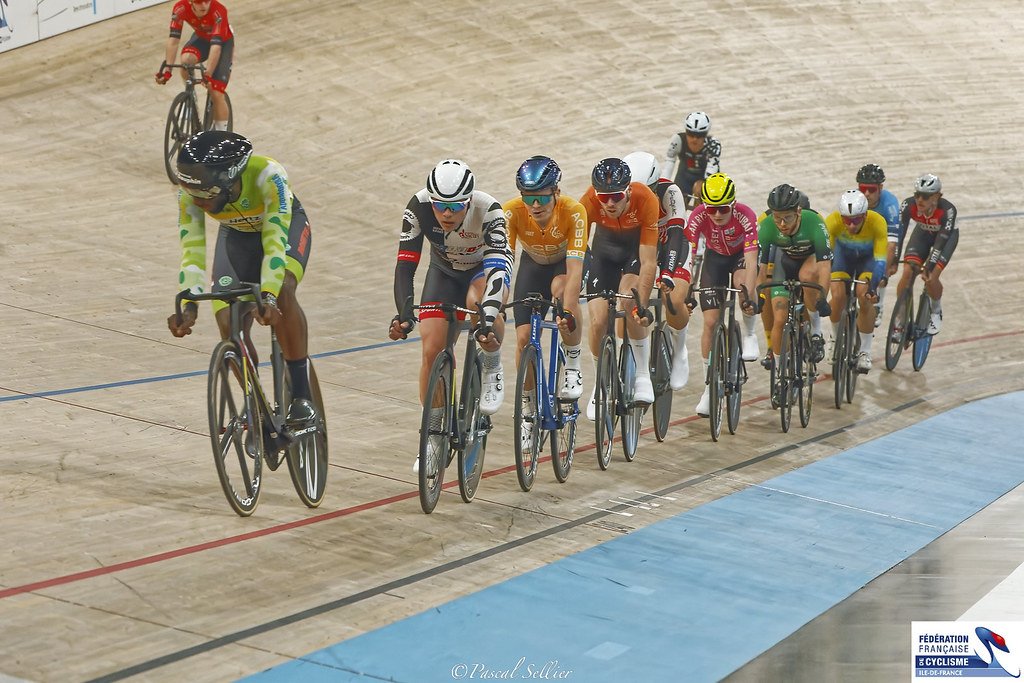 Un peloton de coureurs en file sur l'anneau du Vélodrome National